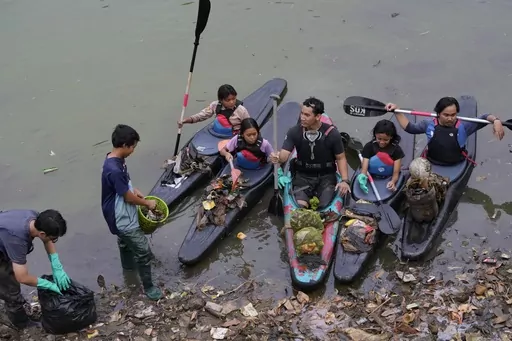 Environmental activist members of the Situ Gede Cleanliness Warrior pick up trash while paddling kayaks at Setu Gede lake in Bogor, West Java, Indonesia, Tuesday, Oct. 10, 2023. Young people have been at the forefront of environmental and climate change movements in recent years: initiatives like school strikes for climate action, protests at United Nations climate talks and around the world, and local clean ups have often been youth-led. (AP Photo/Achmad Ibrahim)