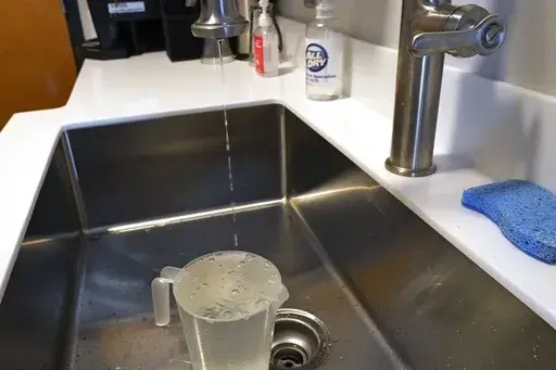 Ted Henifin, head of JXN Water, the corporation that operates the water system for Jackson, Miss., demonstrates how to run a thin line of water from faucets during cold weather on Jan. 12, 2024. JXN Water announced Wednesday, July 10, 2024, that it was shutting off service to some apartment complexes with long-unpaid water bills. (AP Photo/Rogelio V. Solis, File)