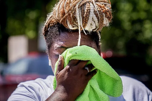 Nicole Brown wipes sweat from her face while setting up her beverage stand near the National Mall on July 22, 2022, in Washington. What's considered officially “dangerous heat” in coming decades will likely hit much of the world at least three times more often as climate change worsens, according to a new study. (AP Photo/Nathan Howard, File)