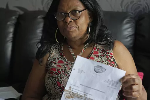 Sadie James shows a document from a housing association at her home, in London, Wednesday, July 12, 2023. For Sadie James, the cost-of-living crisis in Britain just never seems to ease. First, it was skyrocketing energy and food costs stemming from Russia's invasion of Ukraine. Now, the 61-year-old worries whether she can keep a roof over her head. (AP Photo/Kin Cheung)