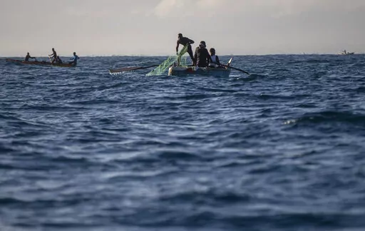 A fisherman pulls his net back onto his boat in the waters surrounding Cap-Haitien, Haiti, Friday, March 11, 2022. A prize winning marine biologist is working to bring together fishermen from Haiti and the Dominican Republic and find a solution that will not only save their livelihoods but also vital marine resources in a region under extreme pressures from climate change. (AP Photo/Odelyn Joseph)