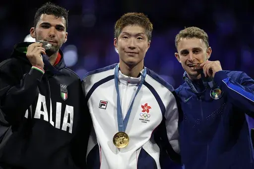 Hong Kong's Cheung Ka long, centre, winner of the gold medal in the men's individual Foil competition, celebrates on the podium with silver medal winner Italy's Filippo Macchi, left, and bronze medal winner United State's Nick Itkin during the 2024 Summer Olympics at the Grand Palais, Monday, July 29, 2024, in Paris, France. (AP Photo/Andrew Medichini)