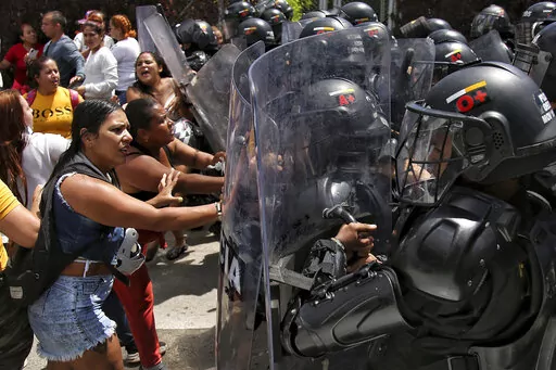 Inmates' relatives push police's shields outside a prison where there was a deadly fire in Tulua, Colombia, Tuesday, June 28, 2022. Authorities say at least 51 people were killed after the fire broke out during what appeared to be an attempted riot early Tuesday. (AP Photo/Andres Quintero)