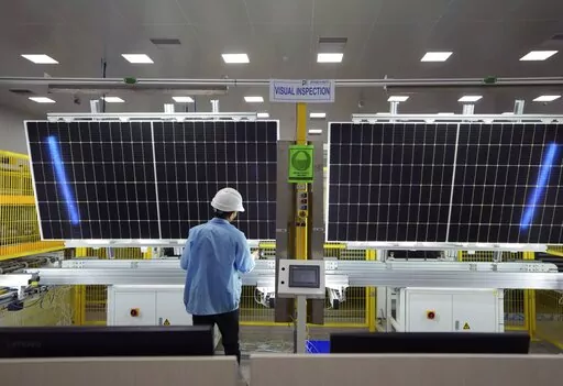 A worker inspects solar panels at Premier Energies Solar on the outskirts of Hyderabad, India, Wednesday, Jan. 25, 2023. Solar developers in India fear that a tax meant to encourage Indian manufacture of solar components will slow down the installation of solar power this year. (AP Photo/Mahesh Kumar A.)