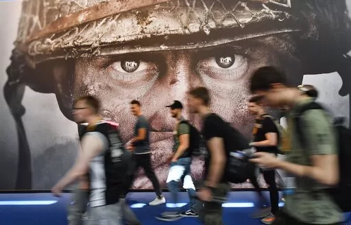 Visitors passing an advertisement for the video game 'Call of Duty' at the Gamescom fair for computer games in Cologne, Germany, Tuesday, Aug. 22, 2017. Microsoft says it struck a deal to make the hit video game Call of Duty available on Nintendo for 10 years when its $69 billion purchase of game maker Activision Blizzard goes through. The announcement Wednesday, Dec. 7, 2022 is an apparent attempt to fend off objections from rival Sony. (AP Photo/Martin Meissner, File)