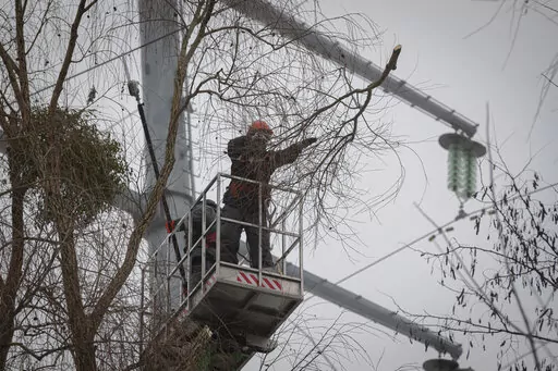 Workers of the electricity supply company DTEK maintain power lines by cutting off excess branches in Kyiv, Ukraine, Thursday, Dec. 8, 2022. Ukrainian utility crews struggling to patch up power lines during a two-month Russian military blitz targeting Ukrainian infrastructure are learning to adapt. And just as on the battlefield, Ukrainians are learning to respond quickly on the new energy front drawn inside homes, hospitals, offices, and schools in yet another act of defiance against a powerful