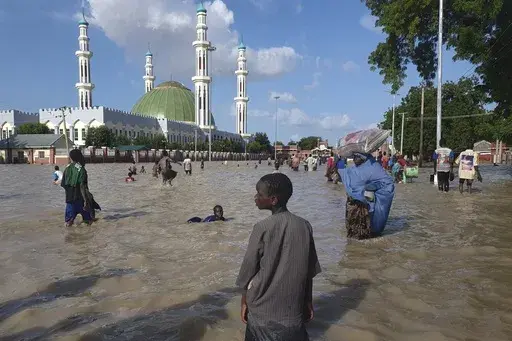 People walk through floodwaters following a dam collapse in Maiduguri, Nigeria, Tuesday, Sept 10, 2024. (AP Photos/ Joshua Olatunji, File)