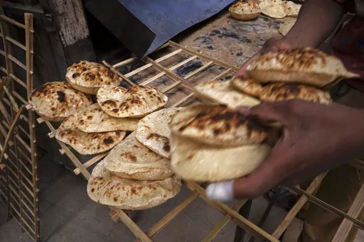 A worker collects Egyptian traditional 'baladi' flatbread, at a bakery, in el-Sharabia, Shubra district, Cairo, Egypt, Wednesday, March 2, 2022. The Russian tanks and missiles besieging Ukraine also are threatening the food supply and livelihoods of people in Europe, Africa and Asia who rely on the vast, fertile farmlands of the Black Sea region. That could create food insecurity and throw more people into poverty in places like Egypt and Lebanon, where diets are dominated by government-subsidiz
