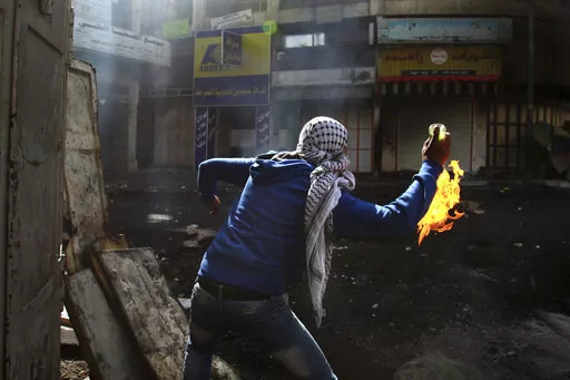 A Palestinian protester throws a Molotov cocktail towards Israeli soldiers during clashes in the West Bank city of Hebron, April 3, 2013. On social media, the world has cheered Ukrainians as they stockpile Molotov cocktails and take up arms against an occupying army. When Palestinians and Iraqis do the same thing, they are branded terrorists and legitimate targets. (AP Photo/Nasser Shiyoukhi, File)
