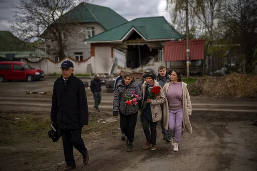 Tetiana Boikiv, 52, center, walks with friends and neighbors during a funeral service for her husband, Mykola "Kolia" Moroz, 47, in the Ukrainian village of Ozera, near Bucha, on Tuesday, April 26, 2022. Russian soldiers took Kolia from his house on March 15. He was tortured and shot, his body found two weeks later in a village 15 kilometers (9 miles) away where Russians set up a major forward operating base for their assault on the capitol, Kyiv. (AP Photo/Emilio Morenatti)