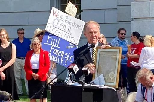 FILE- Jefferson E. Davis, spokesman for a group pushing for a broad review of the 2020 presidential election in Wisconsin, holds up a copy of the Declaration of Independence before leading a group of about 100 people into the state Capitol offices of Republican state leaders asking them to sign subpoenas for access to voting machines, ballots and other election material, on Sept. 10, 2021, in Madison, Wis. The push by Republicans to conduct partisan ballot reviews like the one that unfolded last