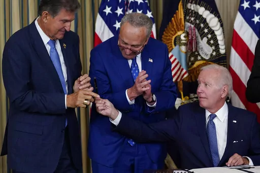 President Joe Biden hands the pen he used to sign the Democrats' landmark climate change and health care bill to Sen. Joe Manchin, D-W.Va., as Senate Majority Leader Chuck Schumer of N.Y., watches in the State Dining Room of the White House in Washington, Aug. 16, 2022. Manchin made a deal with Democratic leaders as part of his vote pushing the party's highest legislative priority across the finish line last month. Now, he's ready to collect. But many environmental advocacy groups and lawmakers 