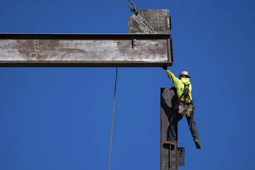 An ironworker guides a beam during construction of a municipal building in Norristown, Pa., Wednesday, Feb. 15, 2023. The strength of the American job market has consistently defied expectations throughout the economic tumult of the COVID years. (AP Photo/Matt Rourke)