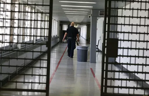 A Rikers Island juvenile detention facility officer walks down a hallway of the jail, Thursday, July 31, 2014, in New York. It's hard to find anyone on board with New York Gov. Kathy Hochul's plan to toughen the state's bail laws, two years after they were retooled to keep people from being jailed because they are poor. The debate over bail in New York has been fierce enough to delay passage of the state's budget. (AP Photo/Julie Jacobson, File)