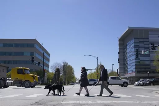 Maureen Reid, left, and her guide dog, Gaston, cross the intersection of Wood Street and Roosevelt Avenue with Sandy Murillo, center, and Geovanni Bahena, relying on an audible signal for the blind, on April 26, 2023, in Chicago. Faced with a growing backlash, the U.S. Census Bureau said Tuesday, Feb. 6, 2024, that it is pausing plans to change how it asks people about disability in its most comprehensive survey, a move that would have overhauled how disabilities are defined by the nation's larg