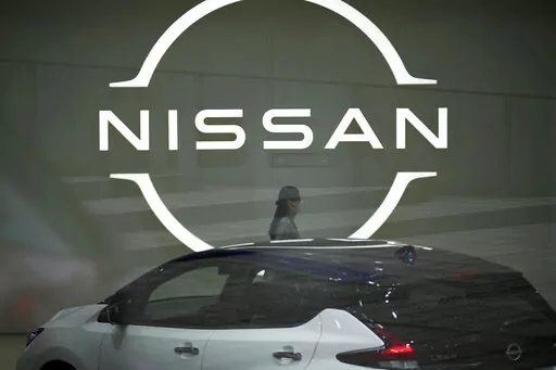 A staff walking near a Nissan logo at Nissan headquarters is seen though a window on May 12, 2022, in Yokohama near Tokyo. Nissan and Renault have changed their mutual cross-shareholdings to the same 15%, ironing out a source of conflict in the Japan-French auto alliance. (AP Photo/Eugene Hoshiko, File)