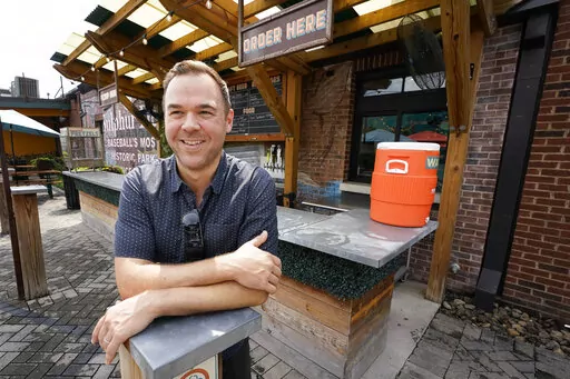 Austin Ray, owner of Von Elrod's Beer Hall And Kitchen, stands in the restaurant's outdoor seating area June 7, 2022, in Nashville, Tenn. For the restaurant, located across the street from Nashville's minor league baseball stadium that sees big crowds in the summer, both inflation and the worker shortage have sent costs skyrocketing. Small businesses that depend on summer crowds and tourism are hoping for a bustling summer this year, boosted by pent up demand after more than two years of the pan
