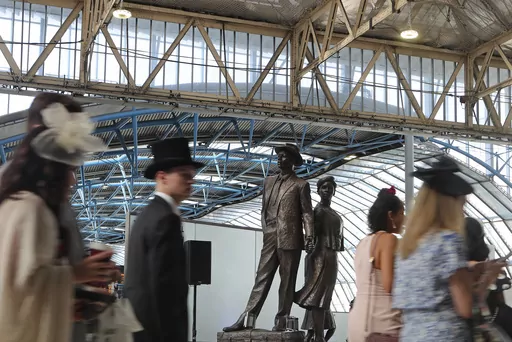 People bound for Royal Ascot race meeting walk past the National Windrush Monument in Waterloo Station in London, Thursday June 22, 2023. Windrush Day is being marked on Thursday on what is the 75th anniversary of the arrival of the ship the Empire Windrush on June 22, 1948. It became a symbol of the post-war migration that transformed the U.K. and its culture. The term Windrush generation has come to stand for hundreds of thousands of people who arrived in the U.K. between the late 1940s and ea