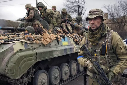 A Ukrainian serviceman walks next to a fighting vehicle, outside Kyiv, Ukraine, Saturday, April 2, 2022. As he begins a second term as France's president, Emmanuel Macron has given the green light for the delivery of artillery pieces to Ukraine. (AP Photo/Vadim Ghirda, File)