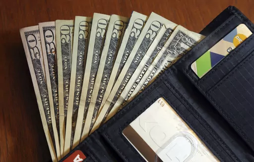 In this June 15, 2018, file photo, cash is fanned out from a wallet in North Andover, Mass. As more states adopt pay transparency laws, many small businesses will need to comply with legislation if they or the candidates they’re sourcing are located within these states. (AP Photo/Elise Amendola, File)