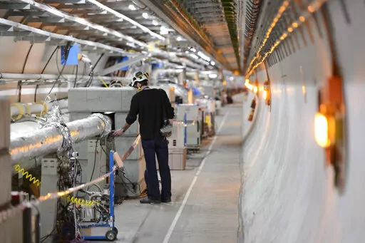 A technician works in the LHC (Large Hadron Collider) tunnel of the European Organization for Nuclear Research, CERN, during a press visit in Meyrin, near Geneva, Switzerland, Feb. 16, 2016. The physics lab that’s home to the world’s largest atom smasher announced on Tuesday, July 5, 2022 the observation of three new “exotic particles” that could provide clues about the force that binds subatomic particles together. The observation of a new type of pentaquark and the first duo of tetraqu
