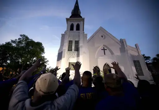 Members of the Omega Psi Phi Fraternity lead a crowd of people in prayer outside the Emanuel African Methodist Episcopal Church after a memorial for the nine people who were shot and killed during Bible study in Charleston, S.C., Friday, June 19, 2015. When violence comes to a public place, as it does all too often in our era, a delicate question lingers afterward: What should be done with the buildings where blood was shed? (AP Photo/Stephen B. Morton, File)