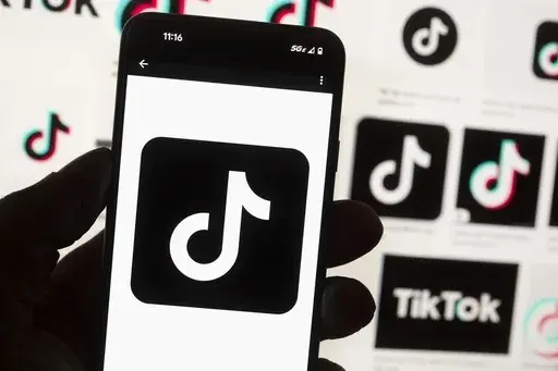 The TikTok logo is displayed on a mobile phone in front of a computer screen, Oct. 14, 2022, in Boston. TikTok is gearing up for a legal fight against a U.S. law that would force the social media platform to break ties with its China-based parent company or face a ban. A battle in the courts will almost certainly be backed by Chinese authorities as the bitter U.S.-China rivalry threatens the future of a wildly popular way for young Americans to connect online. (AP Photo/Michael Dwyer, File)