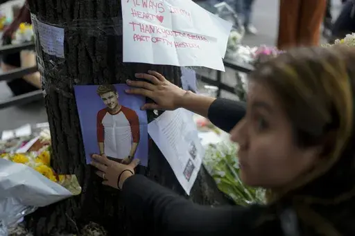 A fan of former One Direction singer Liam places a photo of him on a tree outside the hotel where he was found dead after falling from a balcony the previous day in Buenos Aires, Argentina, Thursday, Oct. 17, 2024. (AP Photo/Natacha Pisarenko)