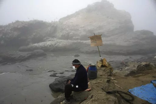 Fisherman Walter de la Cruz sits on the shore of the oil-stained Cavero Beach, unable to fish after a spill in the Ventanilla district of Callao, Peru, Jan. 21, 2022. De la Cruz, 60, is one of more than 2,500 fishermen whose livelihoods have been cast into doubt as a result of a large crude-oil spill by the Spanish-owned Repsol oil refinery on Jan. 15. (AP Photo/Martin Mejia, File)