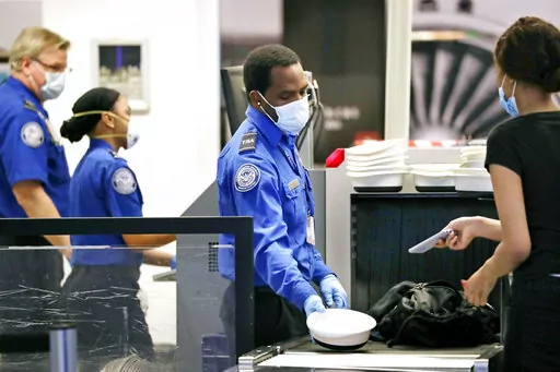 Transportation Security Administration officers process passengers at a security screening area at Seattle-Tacoma International Airport in SeaTac, Wash., on May 18, 2020. With a surge in guns being discovered at airport checkpoints, some security experts are suggesting higher fines and even putting violators on a no-fly list to prevent guns from getting on planes. (AP Photo/Elaine Thompson, File)