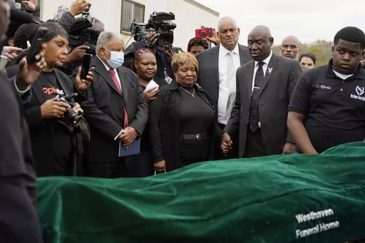 Surrounded by family members and holding hands with civil rights attorney Ben Crump, center right, Bettersten Wade, center, mother of Dexter Wade, a 37-year-old man who died after being hit by a Jackson, Miss., police SUV driven by an off-duty officer, watches her son's body transferred to a mortuary transport in Raymond, Miss. Nov. 13, 2023. An independent pathologist says the deceased Mississippi man had a wallet in the front pocket of the jeans he was buried in that contained his home address