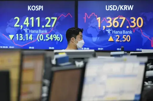A currency trader walks by screens showing the Korea Composite Stock Price Index (KOSPI), left, and the exchange rate of South Korean won against the U.S. dollar, at the foreign exchange dealing room of the KEB Hana Bank headquarters in Seoul, South Korea, Thursday, Nov. 10, 2022. Asian stock markets followed Wall Street lower on Thursday ahead of a U.S. inflation update that will likely influence Federal Reserve plans for more interest rate hikes after elections left control of Congress uncerta