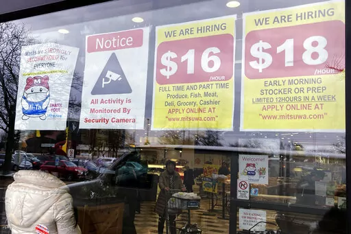 Hiring signs are displayed at a grocery store in Arlington Heights, Ill., Friday, Jan. 13, 2023. On Tuesday, the Labor Department reports on wages and benefits for U.S. workers during the October-December quarter. (AP Photo/Nam Y. Huh, File)