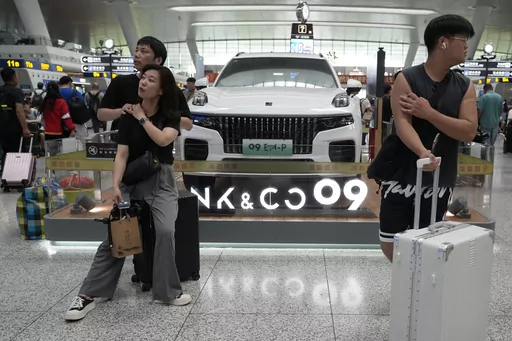 Passengers wait near a hybrid luxury SUV from China automaker Lynk&co displayed at the train station in Hangzhou in eastern China's Zhejiang province on Monday, July 3, 2023. Chinese automakers are winning over drivers as they make major inroads into Europe’s electric vehicle market, challenging long-established homegrown brands in an industry that’s key to the continent’s green energy transition. The European Union has launched an investigation into Beijing’s support for its EV industry