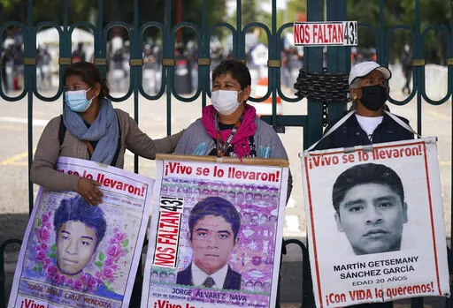 Relatives of the missing 43 Ayotzinapa students hold signs that read in Spanish "You took them alive, We want them back alive" during a protest outside a military base in Mexico City, Friday, Sept. 23, 2022, days before the anniversary of the disappearance of the students in Iguala, Guerrero in 2014. One week prior, Mexican authorities said they arrested a retired general and three other members of the army for alleged connection to their disappearance. (AP Photo/Fernando Llano)