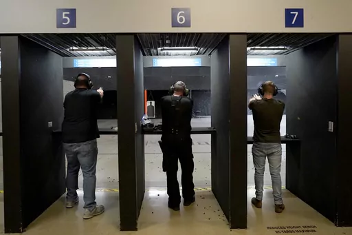 Gun owners fire their pistols at an indoor shooting range during a qualification course to renew their carry concealed handgun permits, July 1, 2022, at the Placer Sporting Club in Roseville, Calif. A California law that bans people from carrying firearms in most public places is taking effect on New Year's Day, even as a court case continues to challenge the law. (AP Photo/Rich Pedroncelli, File)