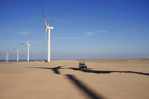 A vehicle drives near wind turbines at Lekela wind power station, near the Red Sea city of Ras Ghareb, some 300 km (186 miles), from Cairo, Egypt, Oct. 12, 2022. The U.N. climate summit is back in Africa after six years and four consecutive Europe-based conferences. The conference — known as COP27 — will be held in the resort city of Sharm el-Sheikh in Egypt. (AP Photo/Amr Nabil, File)