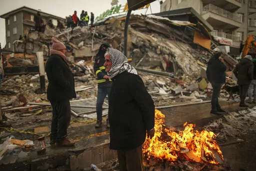 People warm themselves next to a collapsed building in Malatya, Turkey, on Feb. 7, 2023. A magnitude 5.6 earthquake shook southern Turkey on Monday Feb. 27, 2023 three weeks after a catastrophic temblor devastated the region, causing some already damaged buildings to collapse and killing at least one person, the country's disaster management agency, AFAD, said. (AP Photo/Emrah Gurel, File)