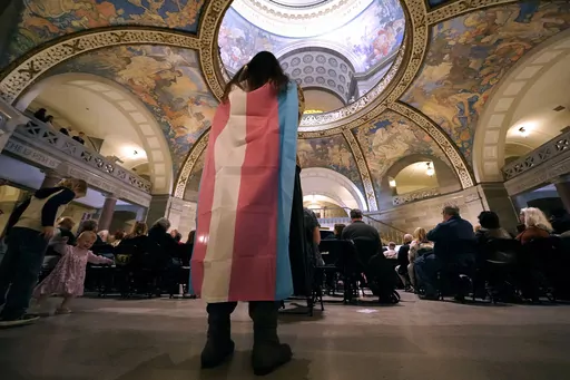 Glenda Starke wears a transgender flag as a counter protest during a rally in favor of a ban on gender-affirming health care legislation, March 20, 2023, at the Missouri Statehouse in Jefferson City, Mo. (AP Photo/Charlie Riedel, File)