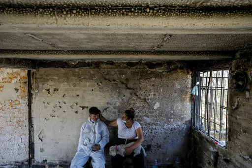 Camila Lange, who is 7-months-pregnant, and her husband Felipe Corvalan sit with their dog Florencia inside their home that was burned by a deadly wildfire in Vina del Mar, Chile, Monday, Feb. 5, 2024. (AP Photo/Esteban Felix)