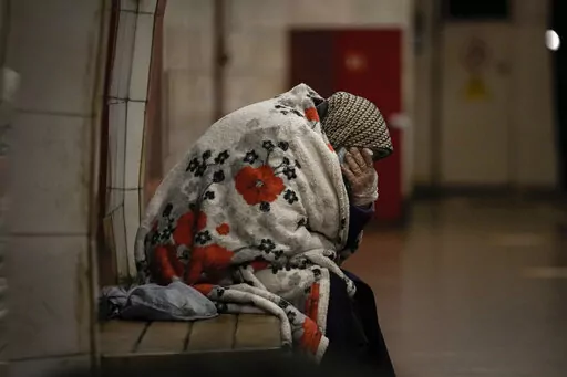 An elderly woman sits on a bench wrapped in a blanket in a subway station turned into a shelter in Kyiv, Ukraine, Tuesday, March 8, 2022. Demands for ways to safety evacuate civilians have surged along with intensifying shelling by Russian forces, who have made significant advances in southern Ukraine but stalled in some other regions. Efforts to put in place cease-fires along humanitarian corridors have repeatedly failed amid Russian shelling. (AP Photo/Vadim Ghirda)