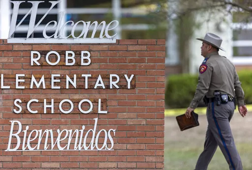 A state trooper walks past the Robb Elementary School sign in Uvalde, Texas, Tuesday, May 24, 2022, following a deadly shooting at the school. (William Luther/The San Antonio Express-News via AP, File)
