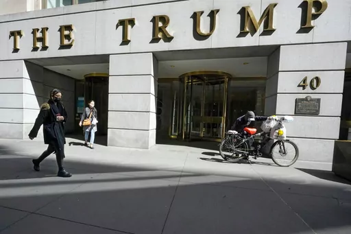Pedestrians and a food delivery man are seen outside the Trump building on Wall Street, in New York's Financial District, March 23, 2021. (AP Photo/Mary Altaffer, File )