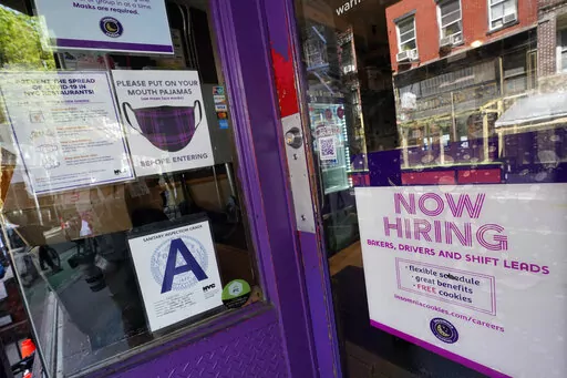 In this May 4, 2021 file photo, a signs announcing they are hiring hangs in the window of a restaurant in the Greenwich Village neighborhood of Manhattan in New York. Starting this week, job-seekers in New York City will have access to a key piece of information: how much money they can expect to earn for an advertised opening. (AP Photo/Mary Altaffer, File)