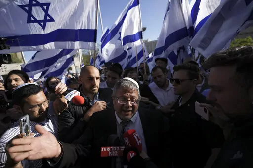 Israeli lawmaker Itamar Ben-Gvir, center, surrounded by right wing activists with Israeli flags, speaks to the media as they gather for a march in Jerusalem, Wednesday, April 20, 2022. Ben-Gvir, an ultranationalist lawmaker who was once relegated to the margins of Israeli politics, is surging in the polls ahead of November’s parliamentary elections. (AP Photo/Ariel Schalit, File)