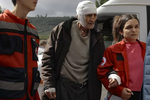 Wounded ethnic Armenian man named Sasha, 84 years-old, from Stepanakert, Nagorno-Karabakh is helped by volunteers walk as he arrives in Armenia's Goris in Syunik region, Armenia, on Wednesday, Sept. 27, 2023. Some 42,500 people, or about 35% of Nagorno-Karabakh's ethnic Armenian population, has left for neighboring Armenia as of Wednesday morning, according to Armenian authorities. Hours-long traffic jams were reported on Tuesday on the road linking Nagorno-Karabakh to Armenia. (AP Photo/Vasily 