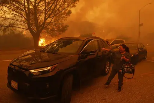 A woman cries as the Palisades Fire advances in the Pacific Palisades neighborhood of Los Angeles, Tuesday, Jan. 7, 2025. (AP Photo/Etienne Laurent)