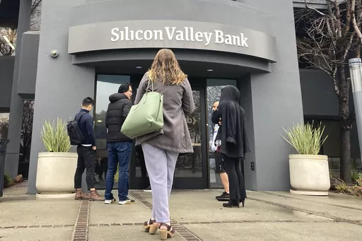 People stand outside a Silicon Valley Bank branch in Santa Clara, Calif., Friday, March 10, 2023. The Federal Reserve is scheduled Friday to release a highly-anticipated review of its supervision of Silicon Valley Bank, the go-to bank for venture capital firms and technology start-ups that failed spectacularly in March. (AP Photo/Jeff Chiu, File)