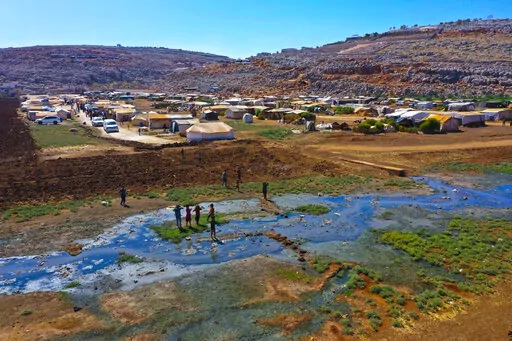 Children play near open sewage in the Salaheddine camp in northwestern Syria on Wednesday, Sept. 28, 2022. In recent weeks, thousands of cholera cases have swept across the crisis-stricken countries of Lebanon, Syria, and Iraq. (AP Photo/Ghaith Alsayed)