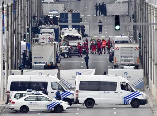 In this Tuesday, March 22, 2016 file photo, police and rescue teams are pictured outside the metro station Maelbeek in Brussels. The trial of 10 men accused over the 2016 suicide bombings at Brussels airport and an underground metro station starts in earnest this week. Survivors, and relatives of the 32 people killed in the deadliest peacetime attacks on Belgian soil, are hoping the trial will bring them closure. (AP Photo/Martin Meissner, File)